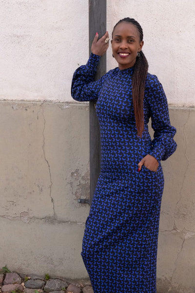 Lång klänning med puffärm och lång manschett, fickor, polokrage, slits baktill och längd till ankeln i tyget Moon blue som har svart grund och blåa månar som mönster från märket Esther & Inez