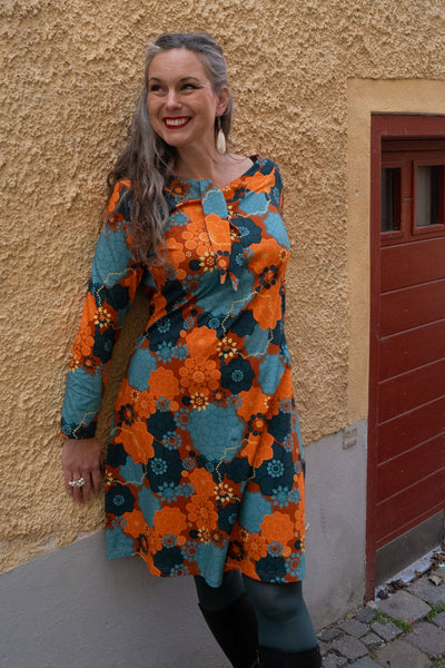 orange blå klänning i blommönster av Zinnia från märket Esther & Inez. Lång ärm längd till ovan knä, båthalsringning med ett slips-knyt